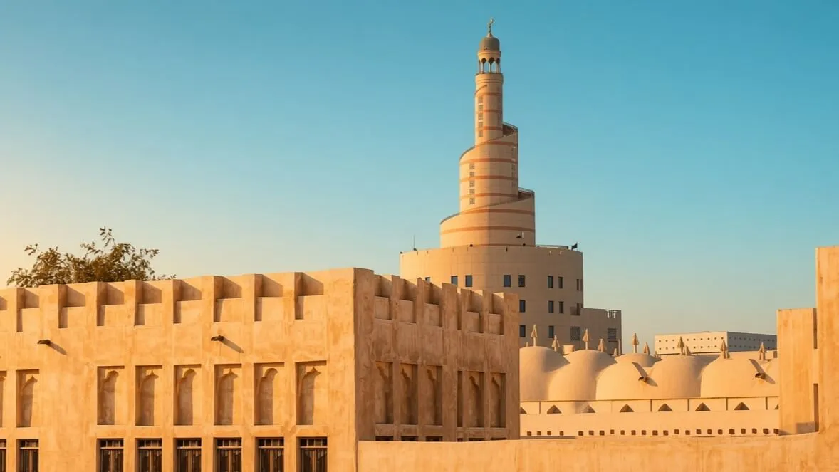 Fanar spiral minaret and domes seen above sandstone walls